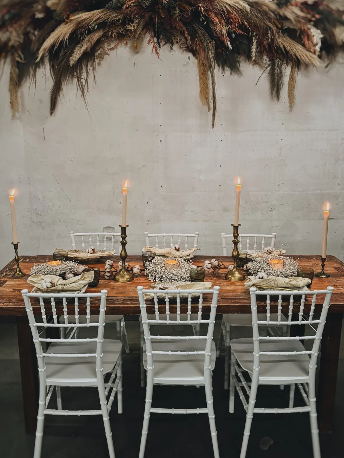 Weiße Chiavaristühle an einer Tafel mit Messingkerzenständern und Pampasgras