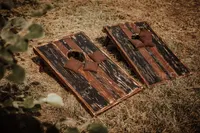 Zwei Cornhole Bretter aus dunklem Holz mit Wurfsäckchen auf Stroh