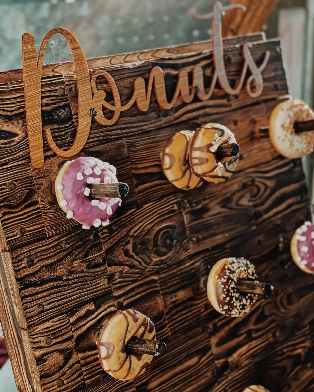 Donut Wall aus Holz mit Schriftzug Donuts und bunten Donuts an Haken