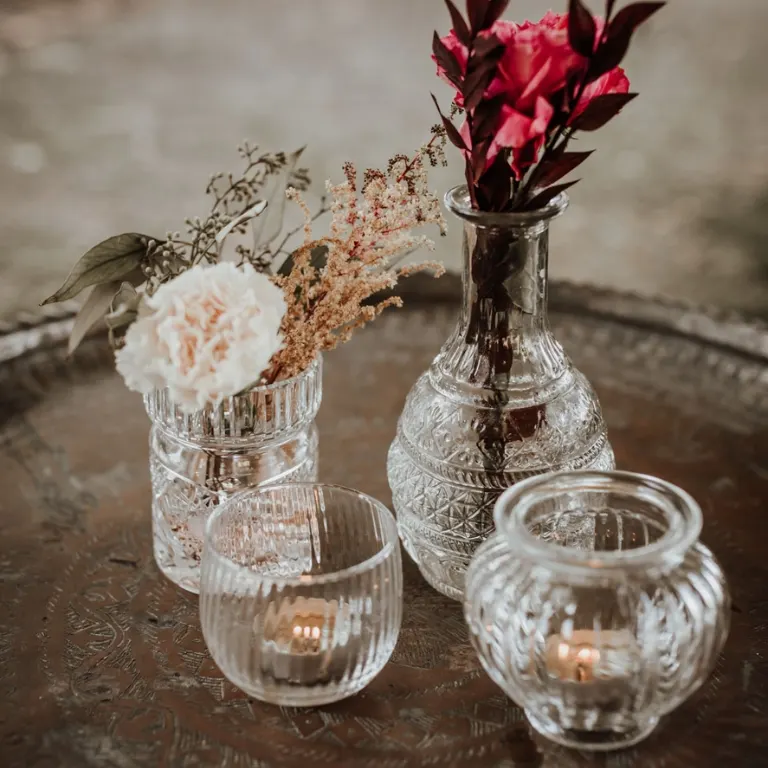 Glasvasen und Kerzengläser mit rosa Blumen auf einem Silbertablett