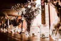 Glasset mit Wiesenblumen und Kerzen bei Abendlicht