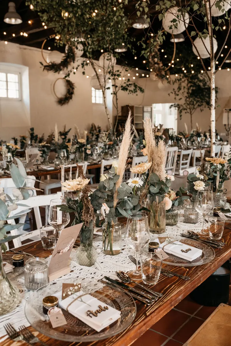 Holztafel unter einem Lichterhimmel mit Blumen und Kerzen