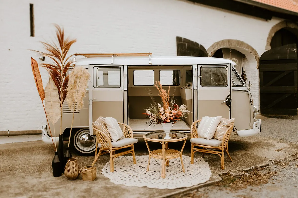 Rattan Lounge mit Sesseln vor einem alten VW Bus