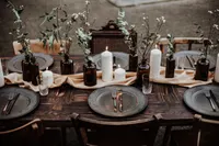 Dunkler Plankentisch mit braunen Apothekerflaschen und grauen Tellern