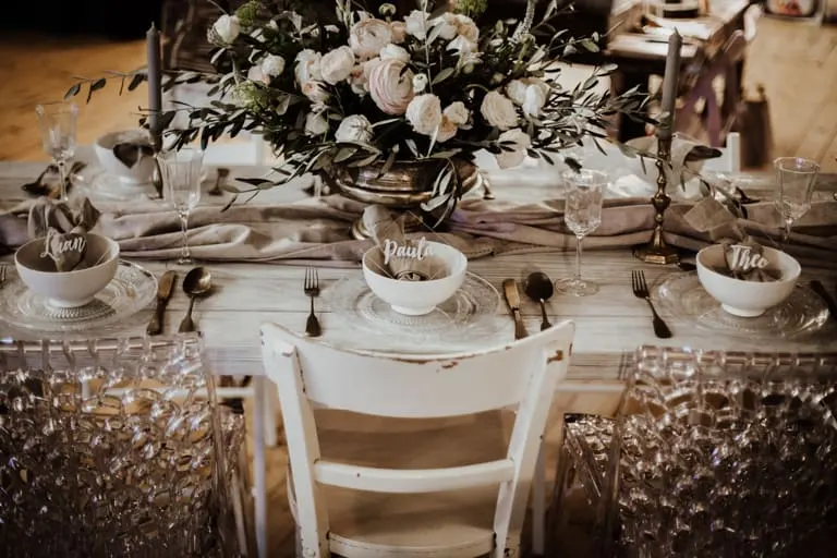 Weißer Plankentisch mit Blumen und Goldbesteck