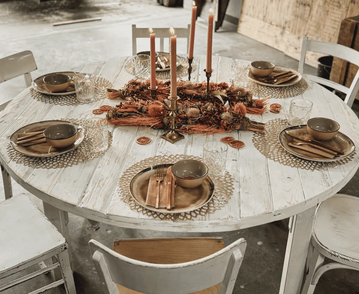 Rundtisch Vintage weiß mieten Weißer Vintage Rundtisch mit Terrakotta Kerzen und Rattan Platzsets