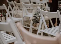 Weiße Klappstühle mit Blumengesteck am Rücken, Nahaufnahme