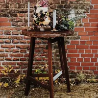 Stehtisch aus dunklem Holz mit Hochzeitstorte vor Backstein