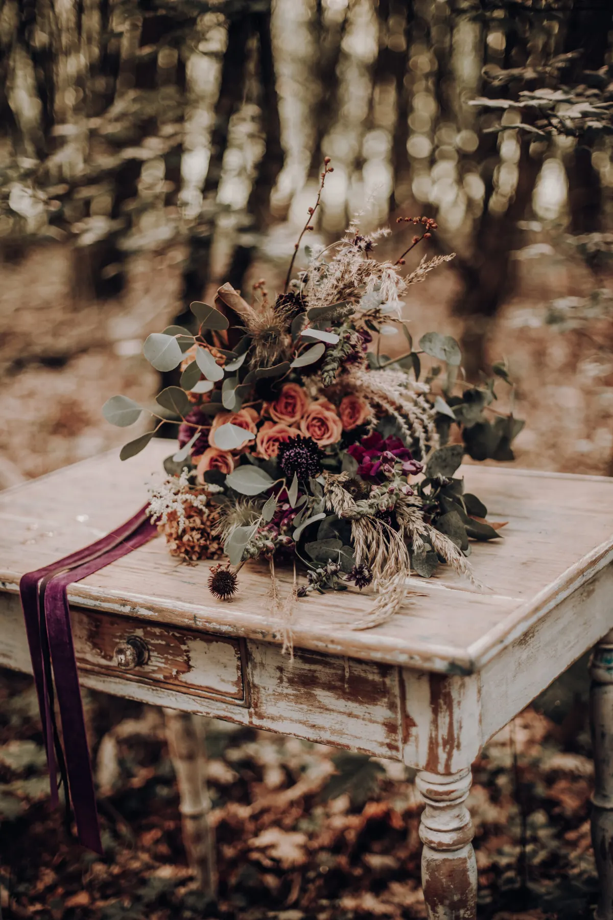 Brautstrauß auf einem weißen Vintagetisch im Herbstwald